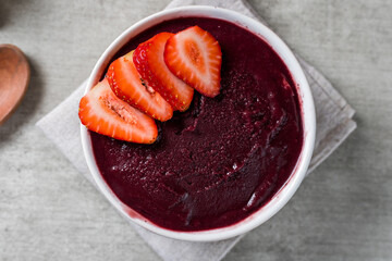 Brazilian frozen açai berry ice cream bowl with strawberries. with fruits on wooden background. Summer menu top view. close up