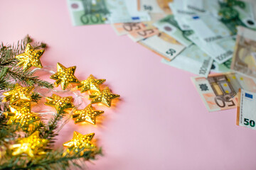 Small pile of paper euro bills and Christmas decoration on pink background. Christmas discounts. sales, business, investment, concept. Flat lay, top view, copy space.
