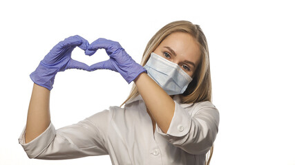 Beautiful young nurse in white robe and medical mask shows love sign with her hands lifting up, looking at the camera. Isolated on white background. 