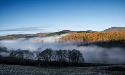 the mist at the bottom of the welsh valley with the top of the mountains peaking out of the clouds