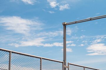 Electrical junction box with conduit pipe connection outside the building and chain Link fence against blue sky background.