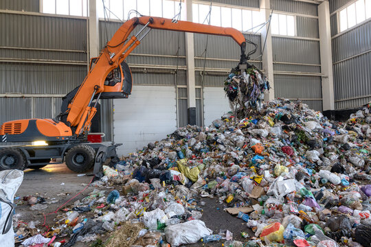 Waste sorting and recycling plant. Loader and grab crane are handling waste