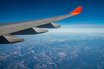 Obraz premium Plane wing with blue clear sky and mountains