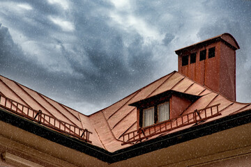 Close-up of a copper roof with dark cloudy sky and rain