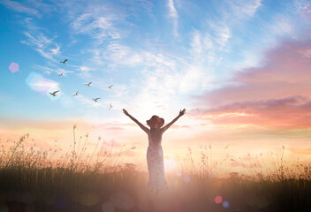 Silhouette of healthy woman raised hands for praise and worship God at autumn sunset meadow...