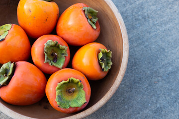 Persimmons in a Wooden Bowl on a ground