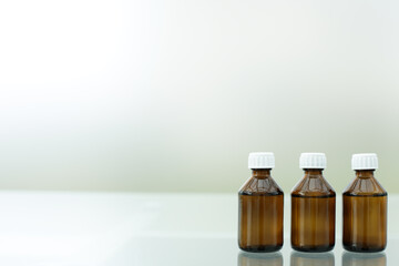 Three medicine bottles stand on a glass table