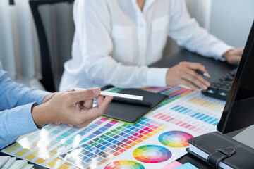 graphic designer team working on web design using color swatches editing artwork using tablet and a...