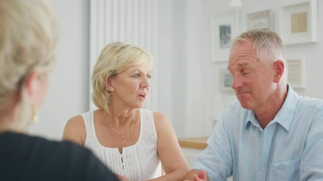 Retired senior couple getting support from female counsellor at home - shot in slow motion