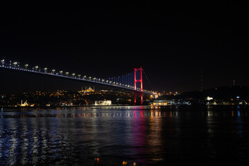Fototapeta na wymiar Bosporus Bridge at night with the city lights reflecting to the sea.Istanbul bridge at night