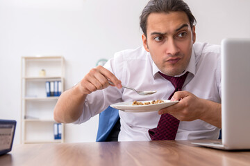 Hungry male employee eating buckwheat during break