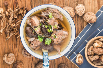 A bowl of mushroom lao duck soup on a cutting board