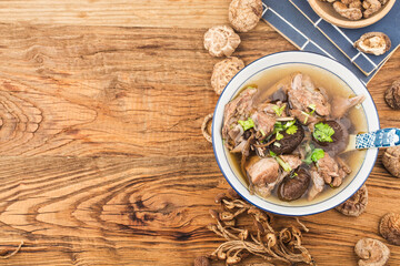 A bowl of mushroom lao duck soup on a cutting board