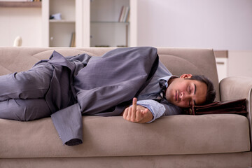 Tired young businessman coming home after working day