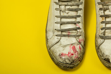 Dirty shoes, vintage white torn sneakers isolated on a yellow background.