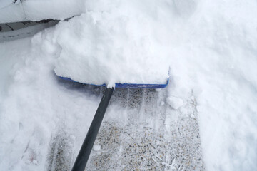 close up on snow shovel removing snow on the driveway