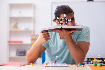 Young male student physicist studying molecular model at home