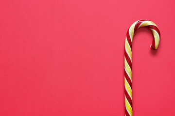 candy cane on a bright red backdrop, top view.