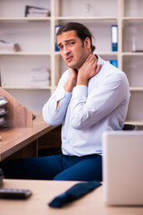 Young male employee suffering from osteochondrosis at workplace