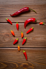 Pods of red and yellow chili peppers lying on a dark wooden surface. Background for spices and...