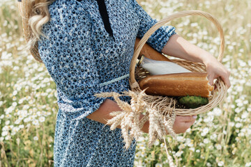 basket with bread, milk and wheat ears in hands of young woman. High quality photo