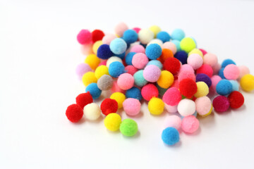 Fur pom-poms on a white background. Multi-colored fluffy balls. Concept - needlework, decor,...