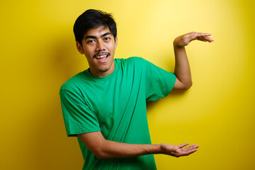 Smiling handsome Asian man pointing finger to empty open hand