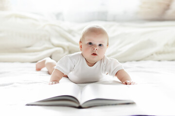 A newborn baby is lying on a soft bed in glasses.