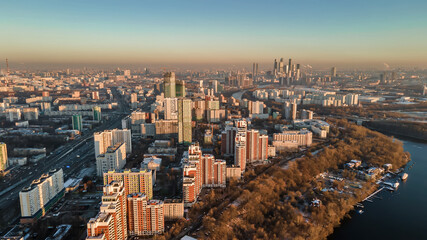 A big and beautiful city from a bird's eye view. City in the rays of the sun at sunset. Park, river, many houses and roads. Beautiful Moscow.