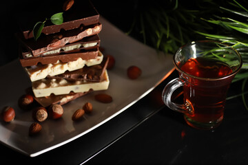 A bar of milk chocolate. Homemade milk chocolate with almonds and dried strawberries. Pieces of milk chocolate. Set of milk chocolate with tea.