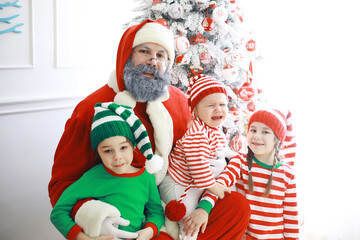 Santa Claus sitting with little cute elves over Christmas background. Time of miracles. Gifts from Santa Claus.