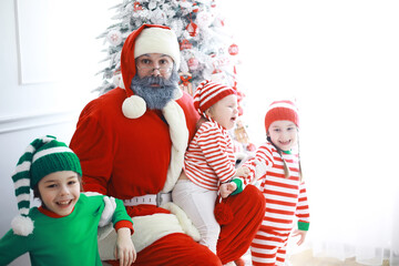Santa Claus sitting with little cute elves over Christmas background. Time of miracles. Gifts from Santa Claus.