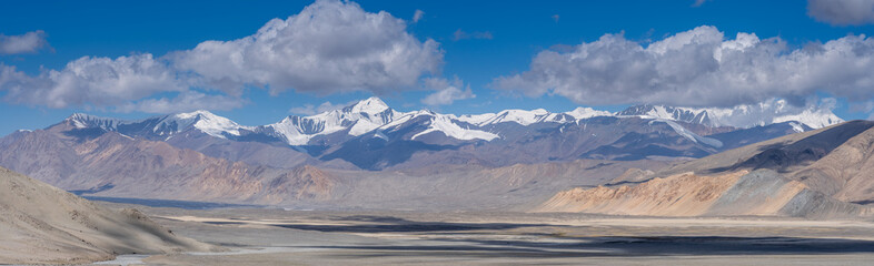 Spectacular panorama with snow-capped mountain range and pastel colors on the high-altitude Pamir...