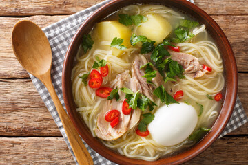 Peruvian Caldo de Gallina Chicken Soup closeup in the plate on the table. horizontal top view from above