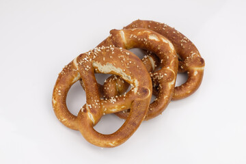 Drei frische salzige Bretzeln liegen schräg gestaffelt / gefächert freigestellt auf einem neutralen weißen Hintergrund