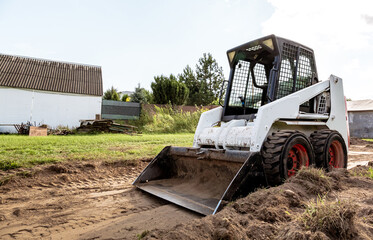 A skid steer loader clears the site for construction. Land work by the territory improvement....