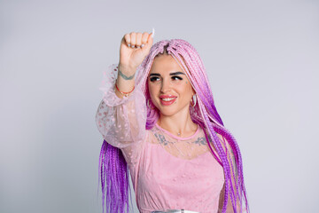 Portrait of a young modern girl with pink braids hair showing fist looking away with a smile. White background.