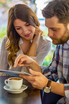 Couple using tablet computer in coffee shop.