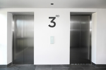 Two Silver Elevator Door in White Hallway.