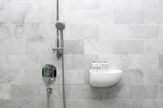 Bathroom hotel amenity, shower gel, shampoo, and conditioner in luxury ceramics container with labels on wooden shelf.