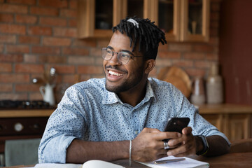Happy young african ethnicity man in eyeglasses looking in distance, feeling excited of getting...