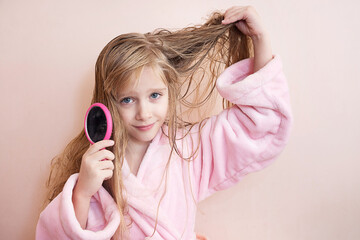 little girl combs her hair after a shower