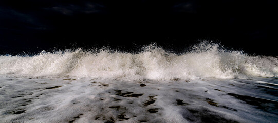 white foam of waves against a black sky