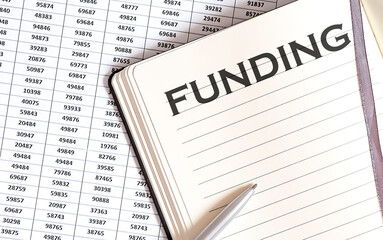 Obraz premium Business concept, on the table a notepad with the text of the FUNDING , profit, loss and graph