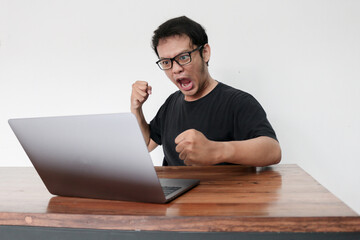Young Asian man is Angry and hate with laptop. Indonesia Man wear black shirt Isolated grey background.