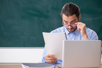 Young male teacher in the classroom in tele-education concept