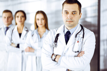 Fototapeta premium Group of professional doctors, standing as a team with crossed arms in a hospital office, ready to help their patients. Medical help, insurance in health care and medicine concept