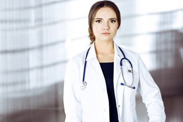 Portrait of a professional friendly woman doctor with a stethoscope, standing straight in a clinic. Physician at work in a hospital. Medicine and healthcare concept