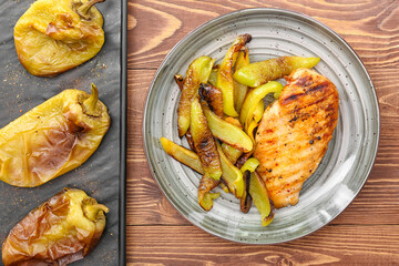 Plate with grilled bell peppers and chicken on wooden table