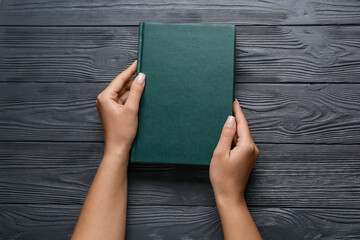 Female hands with blank book on dark wooden background - Powered by Adobe